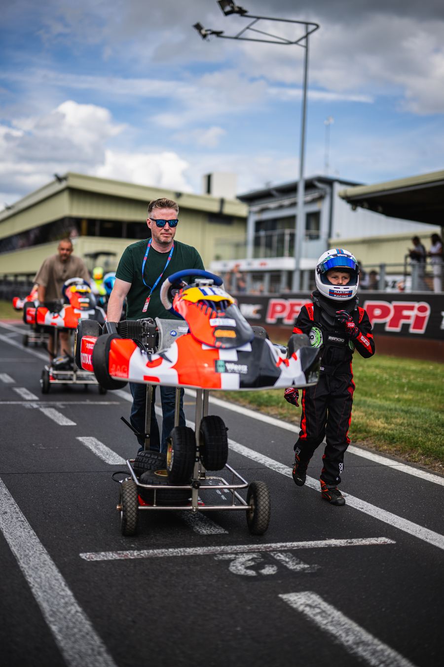 Young driver and parent bringing the kart to the grid